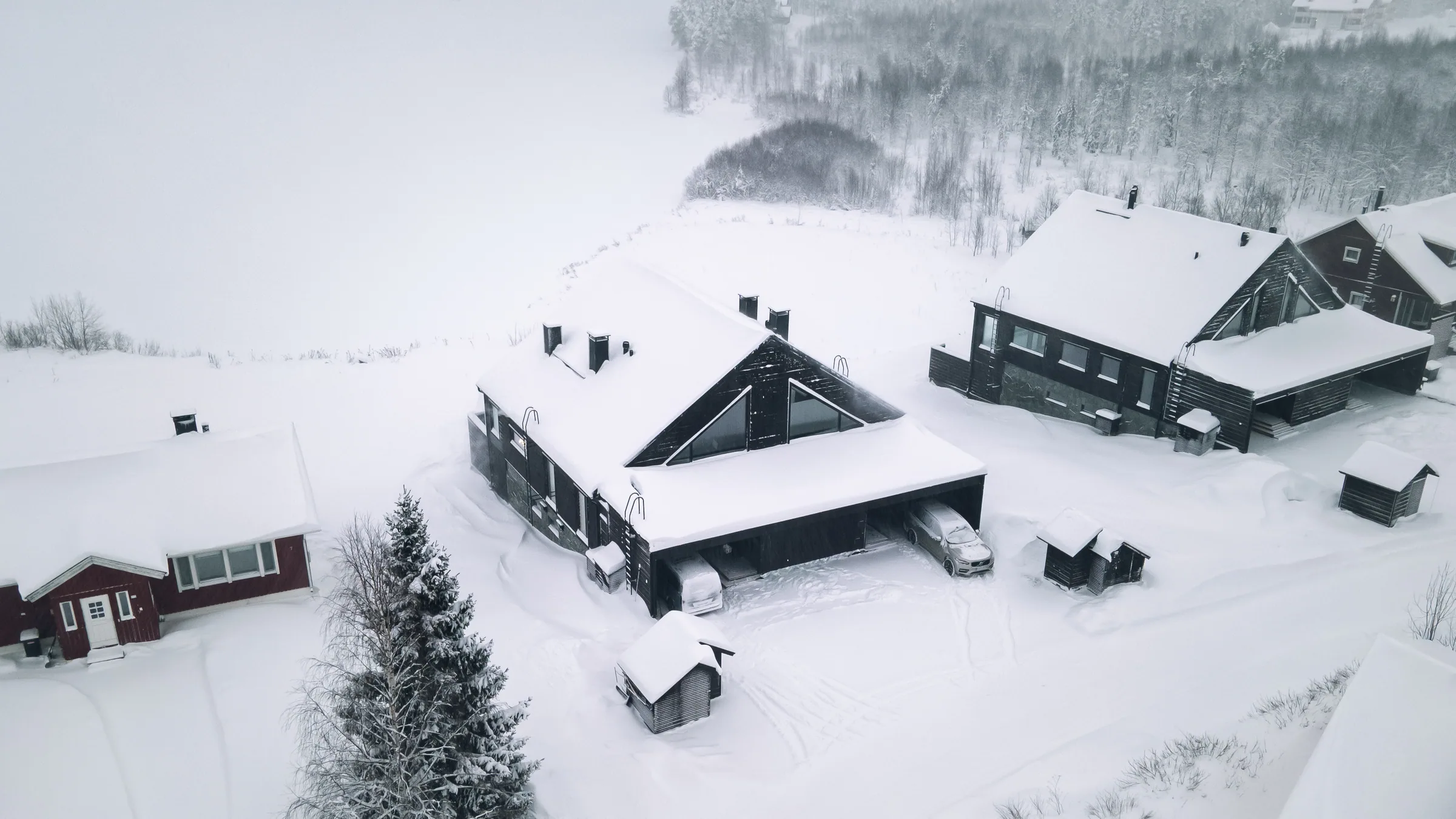 Ilmakuva lumisista huviloista ja pihapiiristä talvella