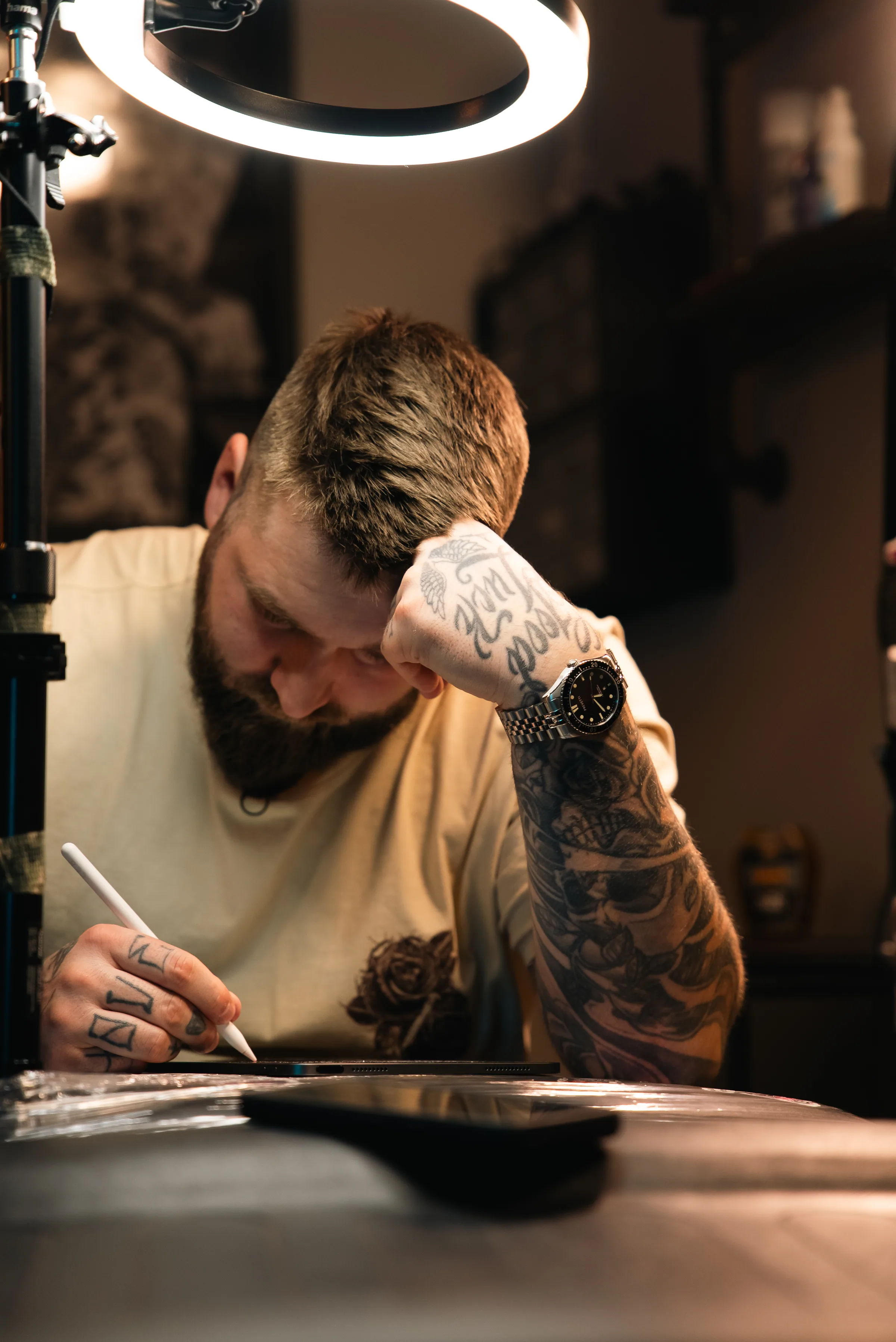 Tatuointitaiteilija keskittyy työhönsä rengasvalon alla studiossa