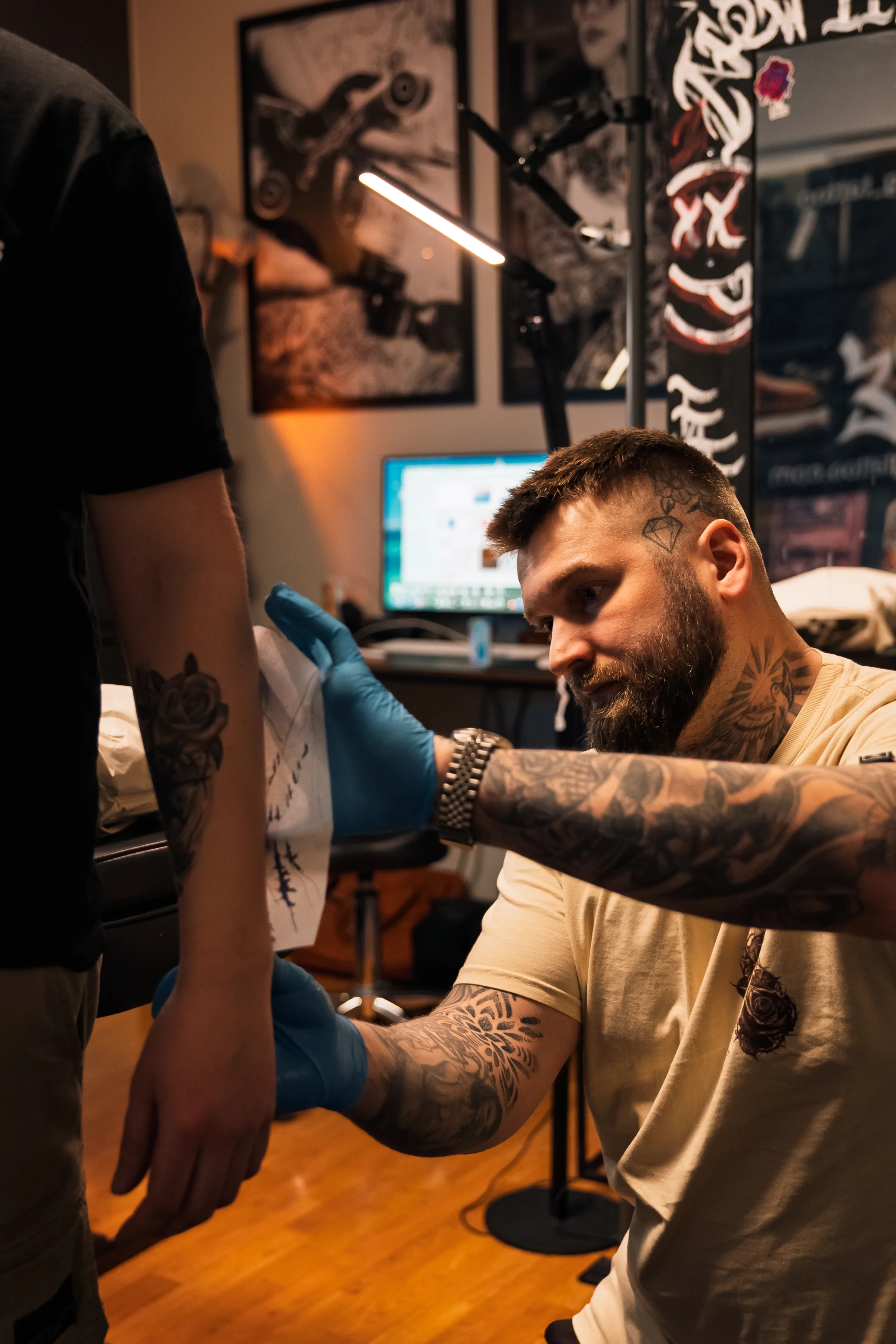 Tatuoija työstää asiakkaan käsivartta tunnelmallisessa tatuointistudiossa