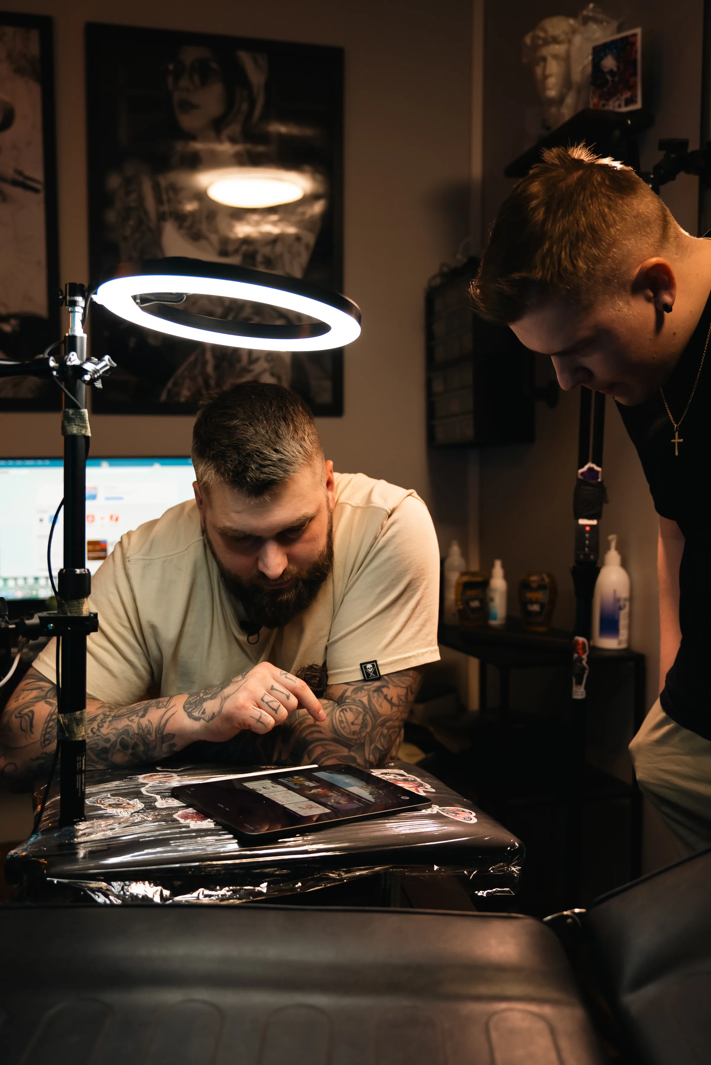 Tatuoija piirtää asiakkaan iholle studion lämpimässä valaistuksessa